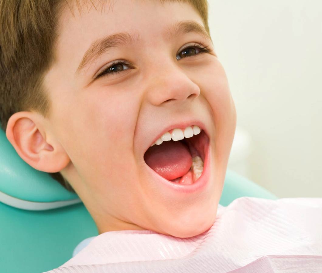 Young boy smiling wide in dental chair during orthodontic examination or treatment.