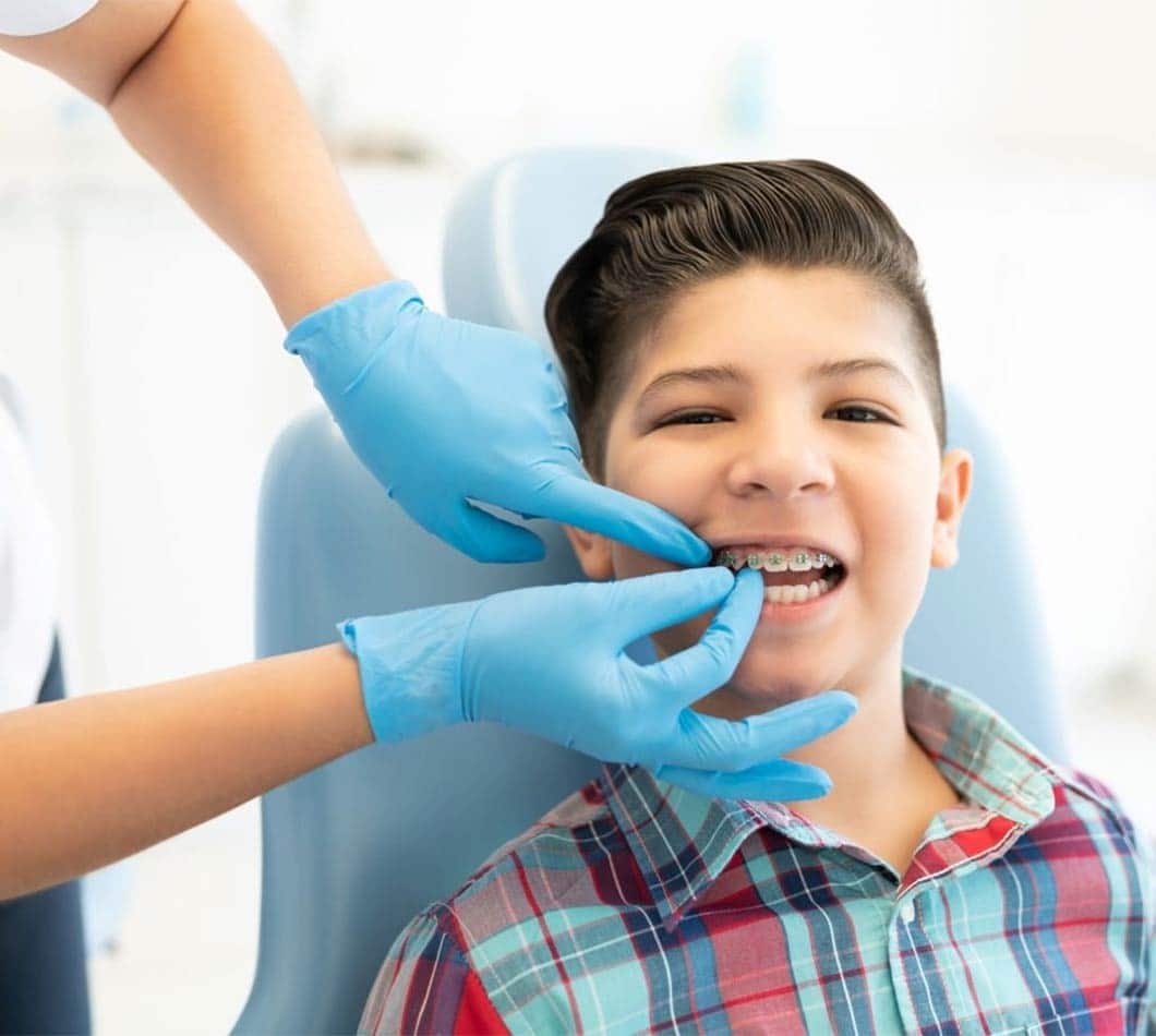 Young boy receiving dental examination from dentist wearing blue gloves in clinical setting.